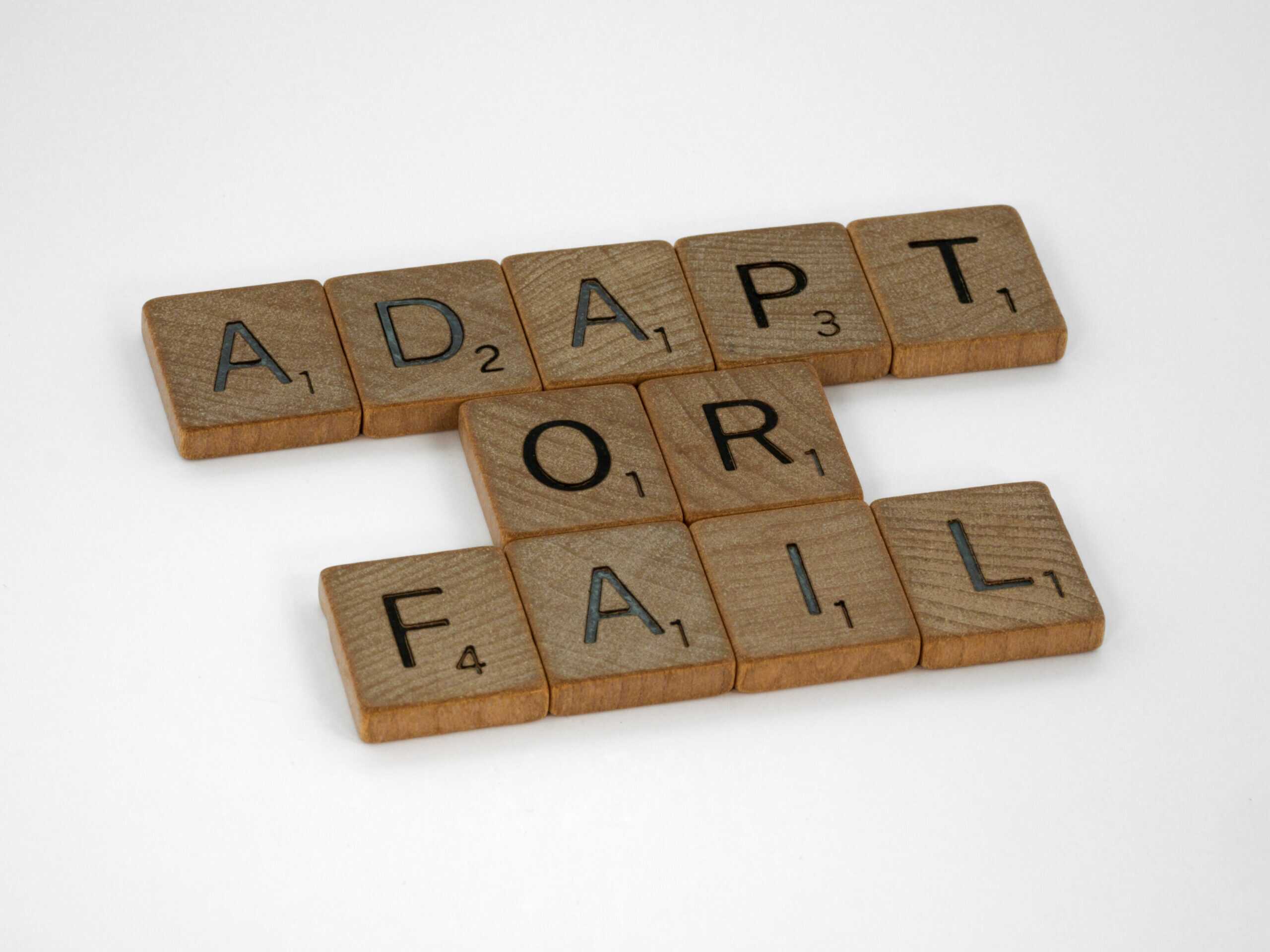 Scrabble letter tiles arranged to spell ADAPT OR FAIL