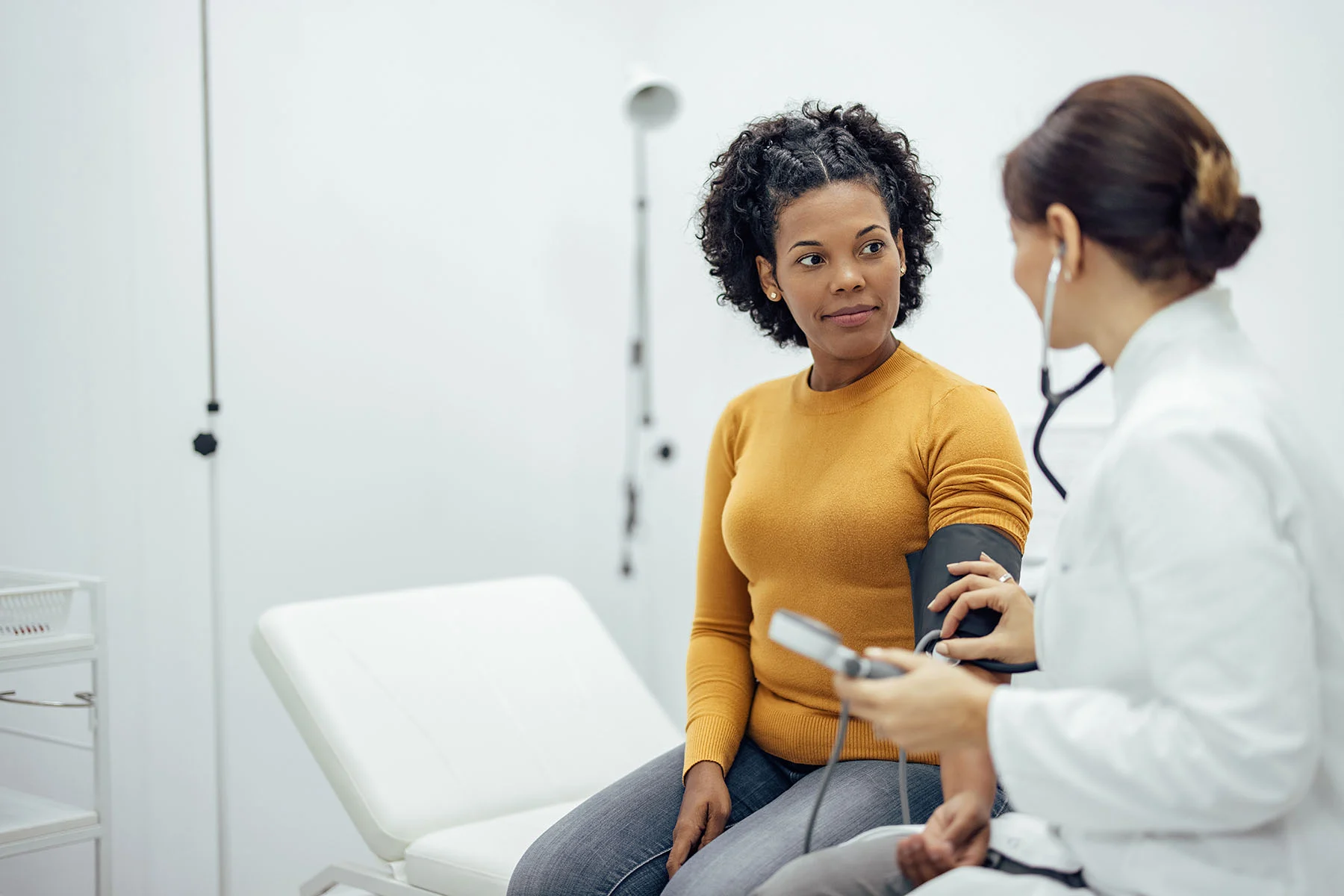 woman getting her blood pressure taken by doctor