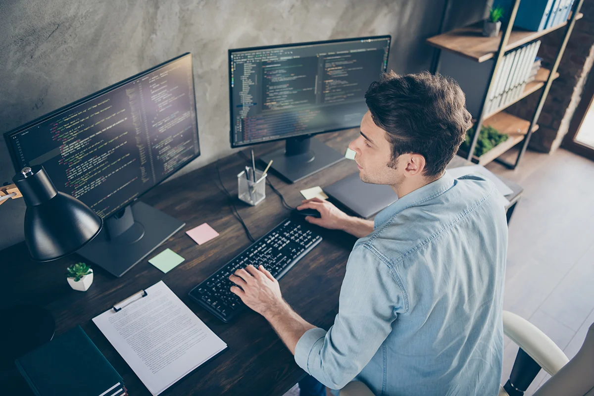 A man sitting in front of computer screens working in IT