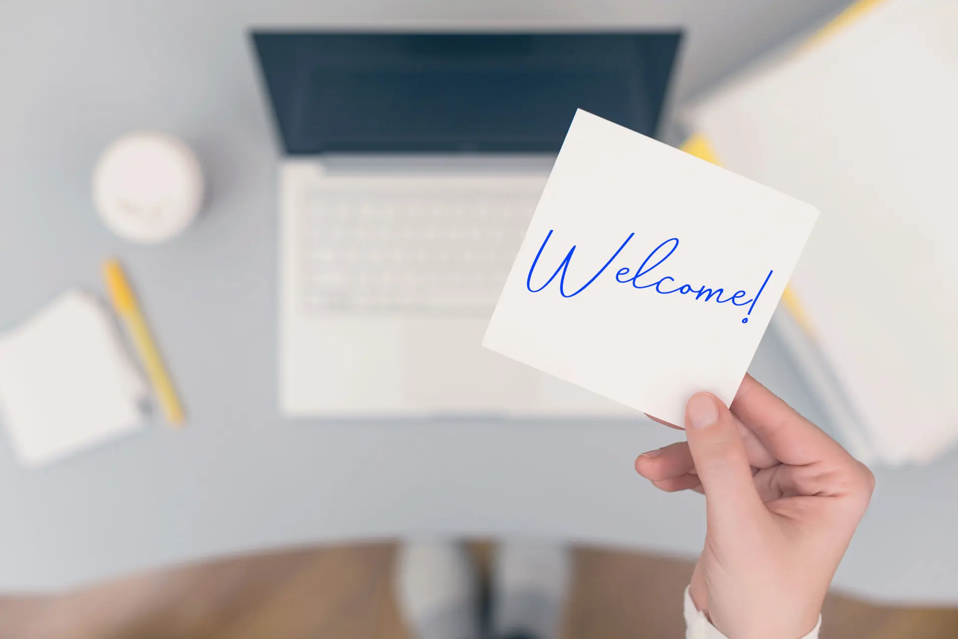 Woman clerk sitting holding note paper sticker with Welcome word. Business concept.